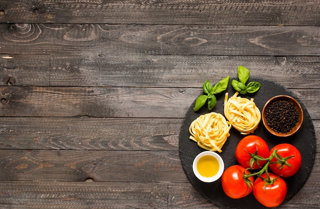 Tagliatelle with tomato and basil, made at home, on a wooden background.