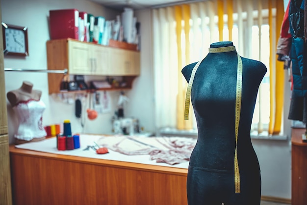 Tailor dummy with measuring tapes in fashion studio