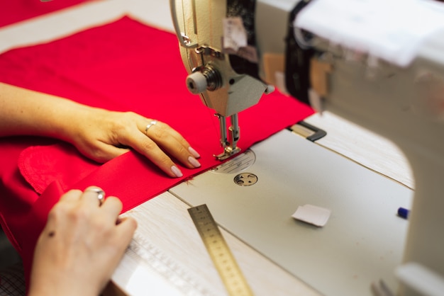 a tailor embroiders with a sewing machine on a crocheted fabric.