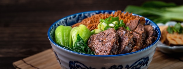 Taiwanese famous food beef noodle with sliced braised beef shank, tripe and vegetables on wooden table background.