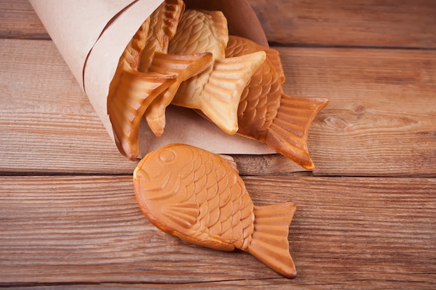 Taiyaki Japanese street food fish-shaped sweet filling waffle on wooden table.