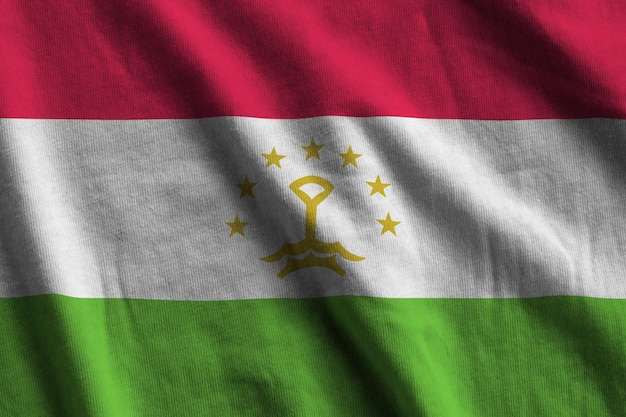 Tajikistan flag with big folds waving close up under the studio light indoors The official symbols and colors in banner