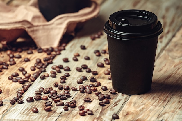 Take away coffee cup and coffee beans on wooden table