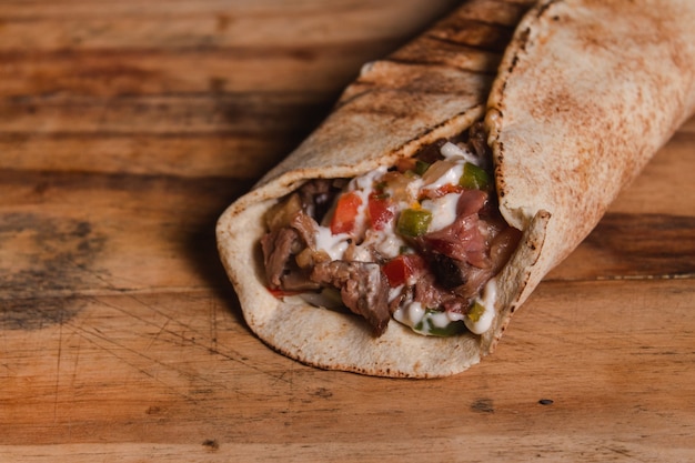 Take detail of an Arabian tenderloin stuffed with sauces on a wooden table.