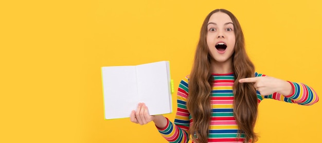 Take a look read a book Surprised girl point finger at open book Read to succeed copy space Banner of schoolgirl student School child pupil portrait with copy space