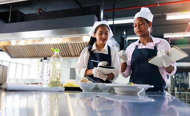 Take note on book Cooking class culinary classroom group of happy young woman multiethnic students are focusing on cooking lessons in a cooking school