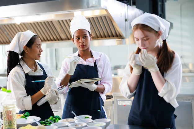 Take note on book Cooking class culinary classroom group of happy young woman multiethnic students are focusing on cooking lessons in a cooking school