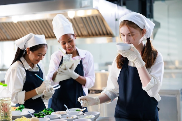 Take note on book Cooking class culinary classroom group of happy young woman multiethnic students are focusing on cooking lessons in a cooking school