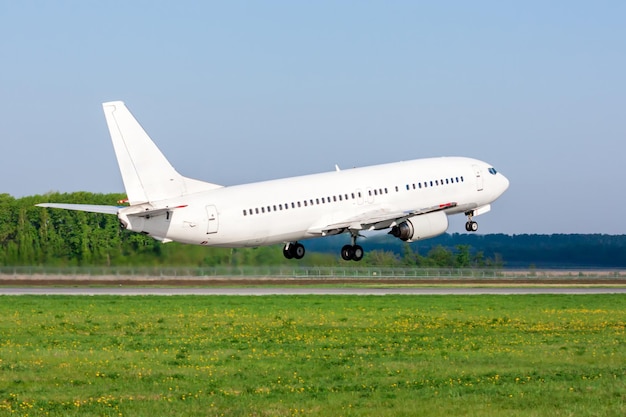 Take-off from the airport runway of a white passenger airplane on a clear summer day