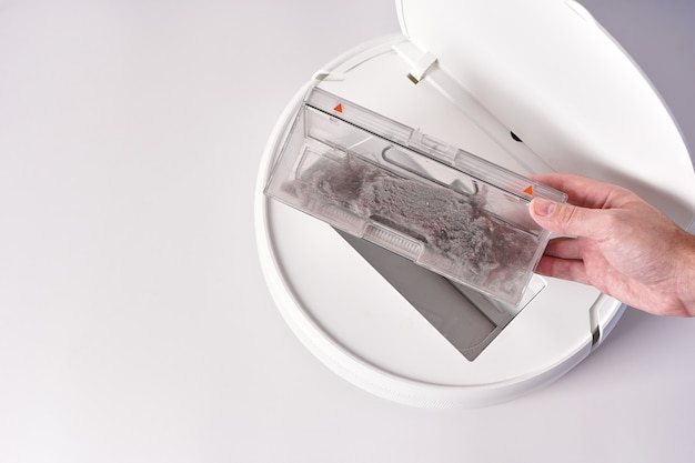 Take out the transparent dust container from the robot vacuum cleaner after cleaning the house. The container is completely clogged with dust