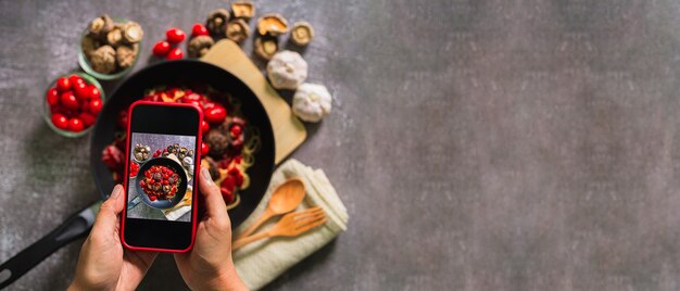 Take a photo of spaghetti with a mobile phoneTop view of woman taking photo on dishes