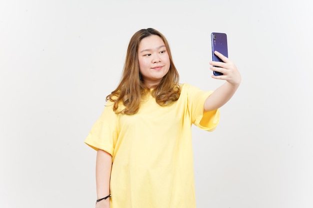 Take a Selfie using Smartphone of Beautiful Asian Woman wearing yellow TShirt Isolated On White