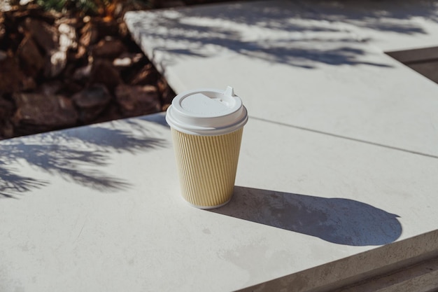 Takeout coffee paper cup on stone bench in business district