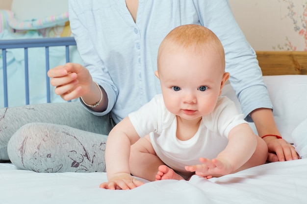 Taking care of the baby mom and baby play on the bed the child busy playing kid wants to play a happy family