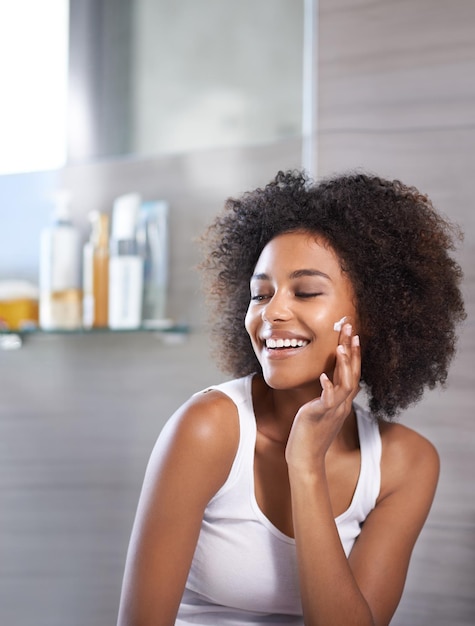 Taking care of my skin. An attractive young woman applying cream to her face.