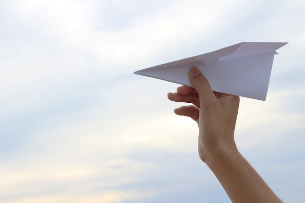 Taking flight! Hand holding paper airplane in the sky