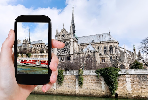 Taking photo of Notre Dame Paris and tourist boat