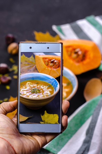 Taking a photo with smartphone of the pumpkin cream soup