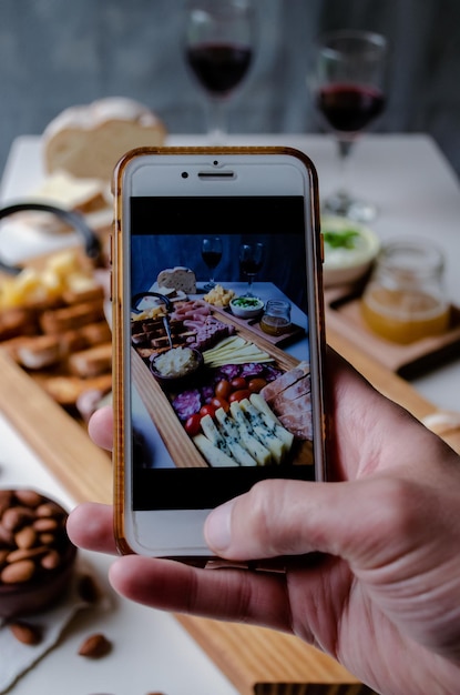 Taking photograph of food served on the table with your smartphone Charcuterie Picada Argentina