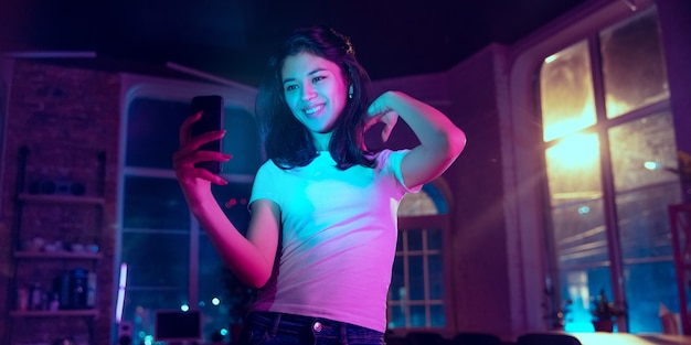 Taking selfie vlog Cinematic portrait of handsome stylish woman in neon lighted interior