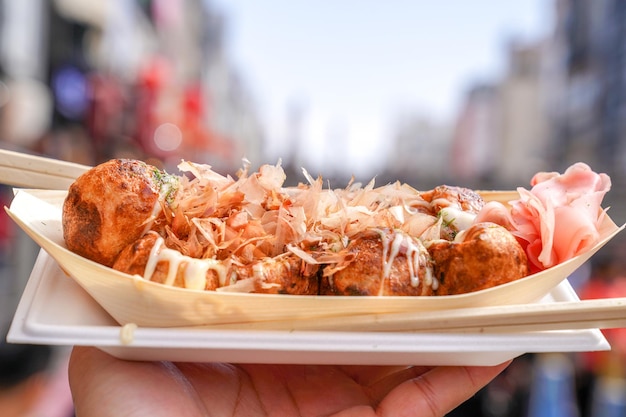 Takoyaki Local Japanese octopus meat ball in the hand with blur cityscape ready to eat