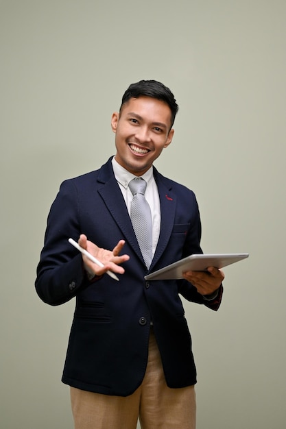 Talented Asian businessman in formal suit holding a tablet standing against isolated background