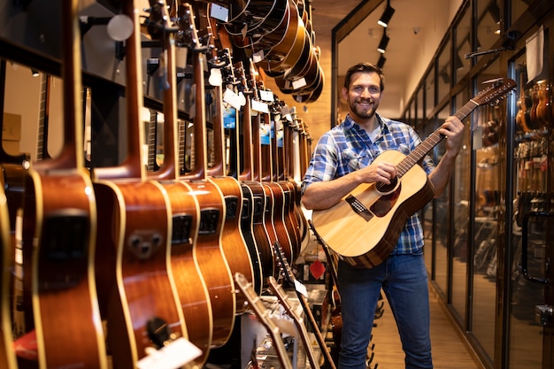 Talented caucasian musician testing new guitar instrument in music shop.