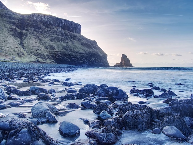 Talisker bay on the isle of skye in scotland foamy sea boulders and large cracked rocks in ocean