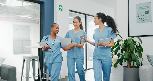 Talking nurses walking and documents in hospital teamwork diversity collaboration or bonding on surgery or clinic break Smile happy and healthcare women with medical research paper or funny joke