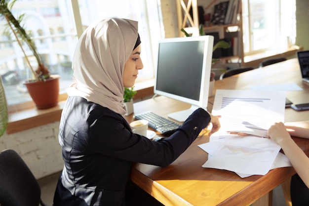 Talking on phone attented Beautiful arabian businesswoman wearing hijab while working