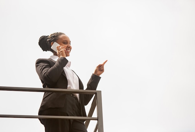 Talking phone, pointing. African-american businesswoman in office attire smiling, looks confident happy, busy. Finance, business, equality and human rights concept. Beautiful young model, successful.