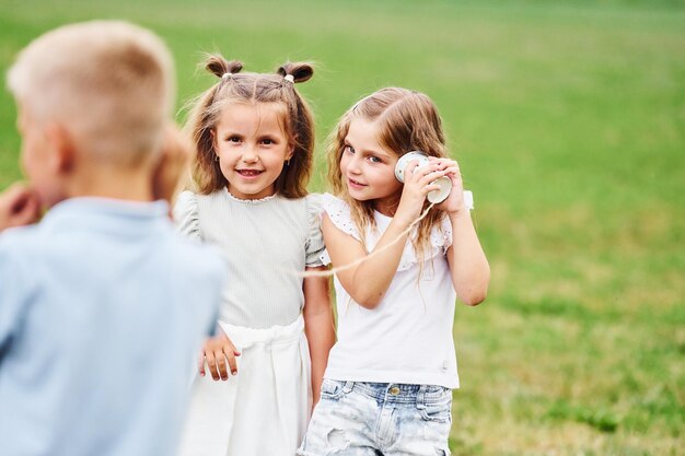 Talking using string can toy Kids are having fun on the field at daytime together