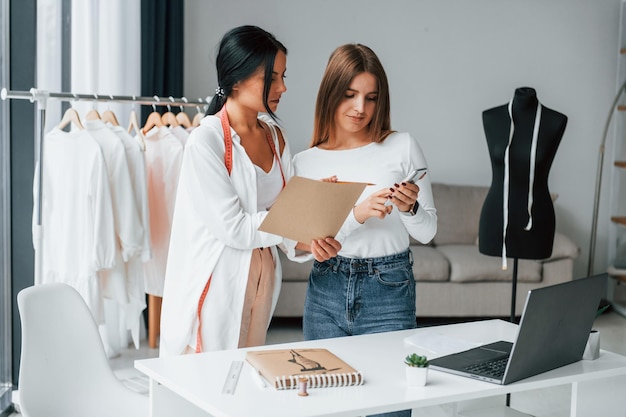 Talking with female customer Seamstress is in her office that is with different clothes