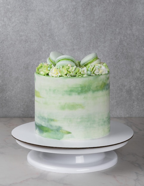 Tall cake with green cream and decor of macarons