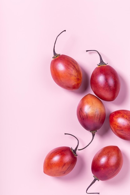 Tamarillo fruit on pink pastel paper background minimal flat lay