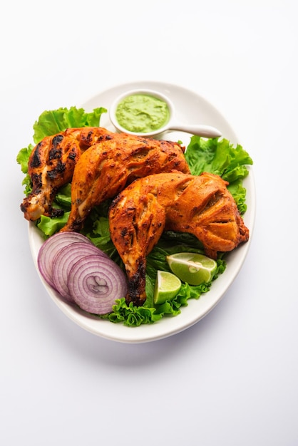 Tandoori chicken is a chicken dish prepared by roasting chicken marinated in yogurt and spices in a tandoor or a clay oven, served with onion and green chutney