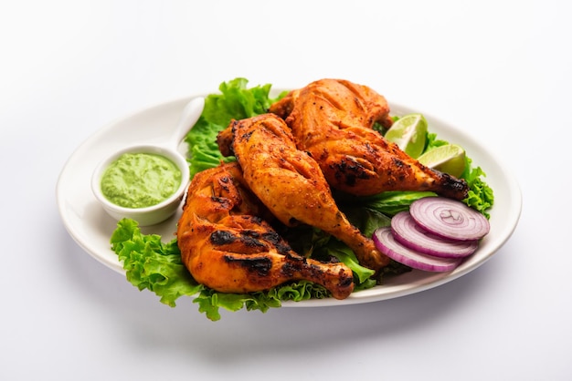 Tandoori chicken is a chicken dish prepared by roasting chicken marinated in yogurt and spices in a tandoor or a clay oven, served with onion and green chutney