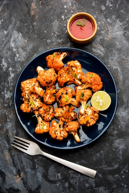 Tandoori Gobi or Roasted cauliflower Tikka is a dry dish made by roasting Cauliflowers in Oven, Tandoor. It's  popular starter food from India. served with ketchup. selective focus