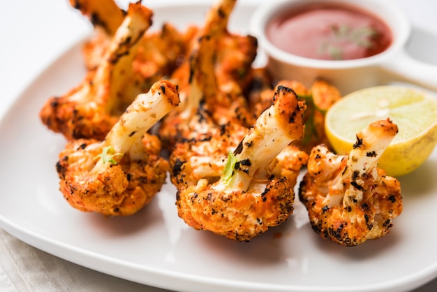 Tandoori Gobi or Roasted cauliflower Tikka is a dry dish made by roasting Cauliflowers in Oven, Tandoor. It's  popular starter food from India. served with ketchup. selective focus