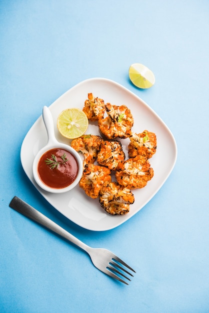 Tandoori Gobi or Roasted cauliflower Tikka is a dry dish made by roasting Cauliflowers in Oven, Tandoor. It's  popular starter food from India. served with ketchup. selective focus