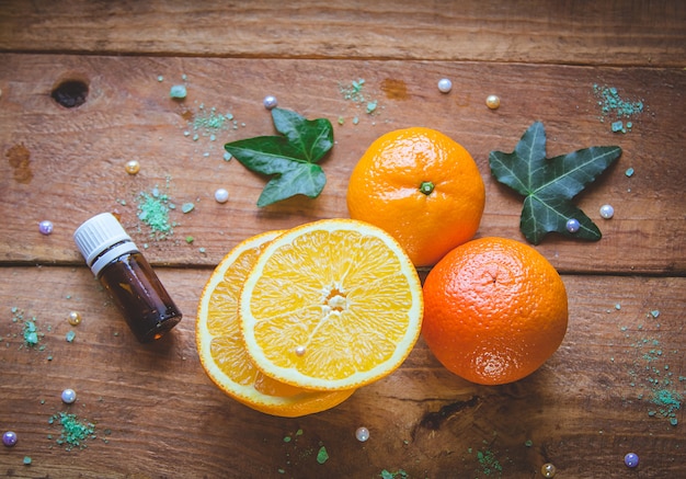 Photo tangerine, orange, and essential bottle on wooden background