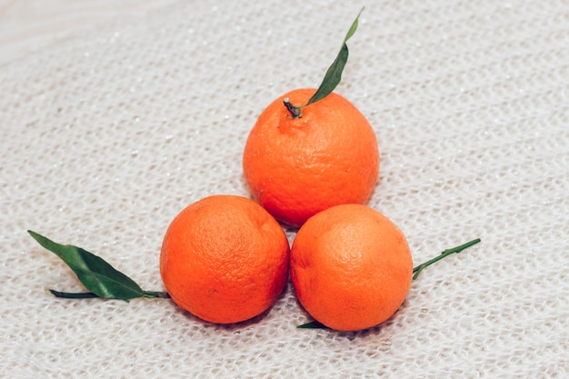 Tangerines on the background of a knitted white cozy sweater