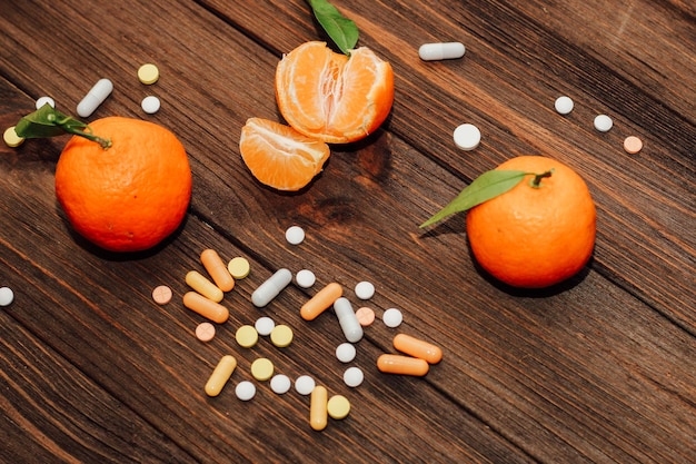 Tangerines on the background of a wooden table with vitamins and pills