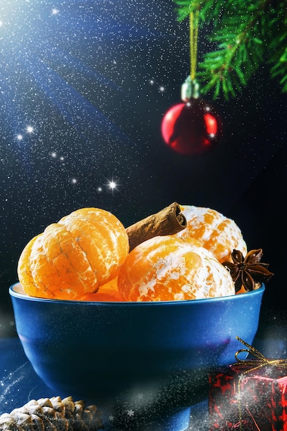 Tangerines in bowl with tubes of cinnamon and star anise