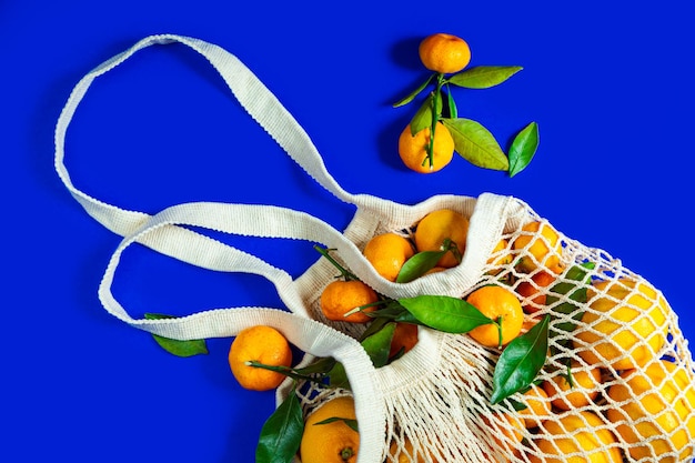 Tangerines in a string bag on a blue background