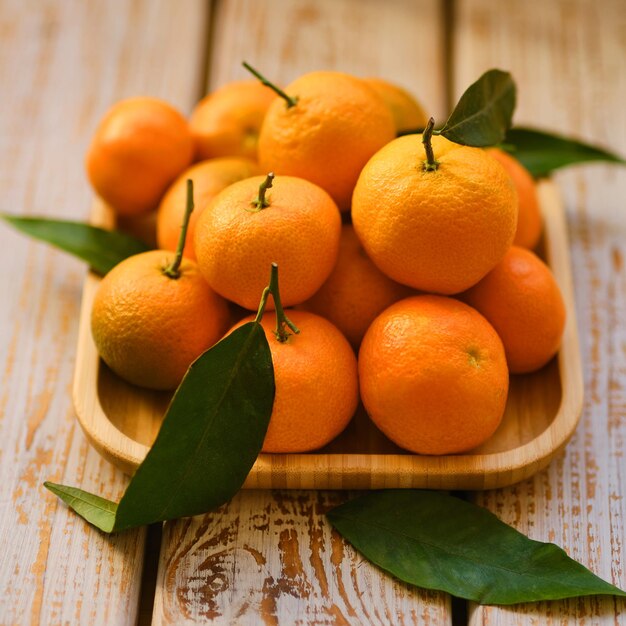 Tangerines with leaves on a rustic wooden background