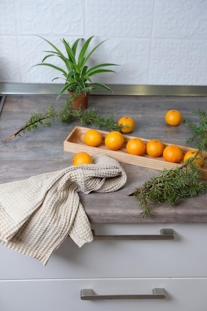 Tangerines on a wooden plate in a white kitchen. New Year's mood, the holiday is coming