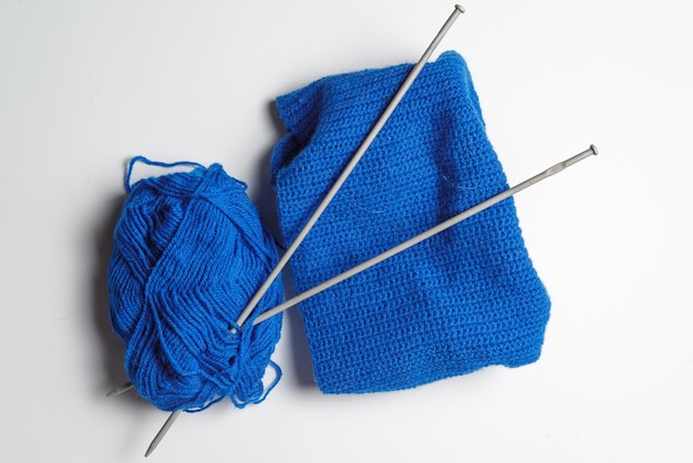 A tangle of blue yarn with two spokes threaded on a gray background. knitting, needlework