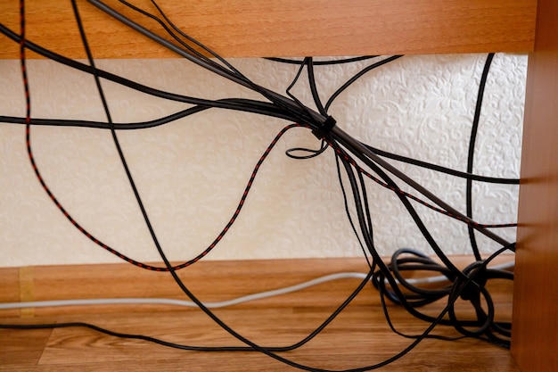 Tangled wires and cable under the table