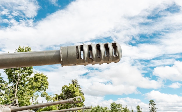 Tank muzzle over cloudy sky background and trees War military concept